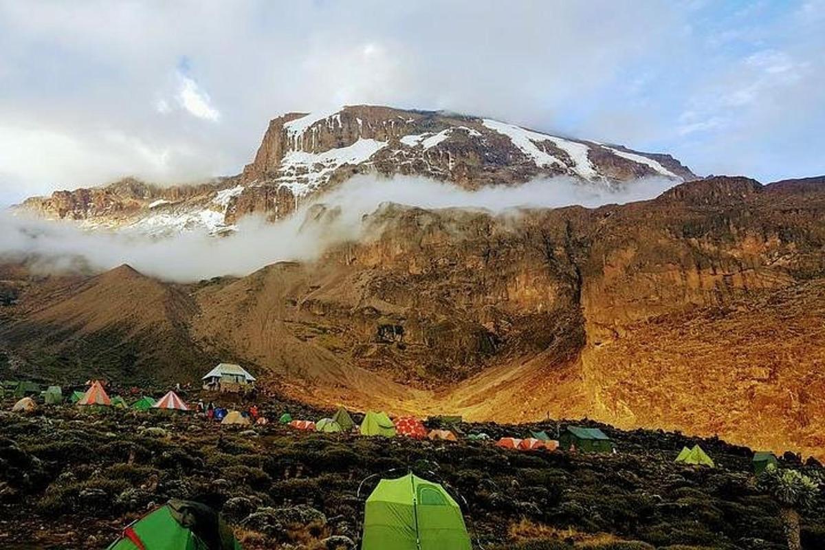 a mountain with tents and a snow covered mountain