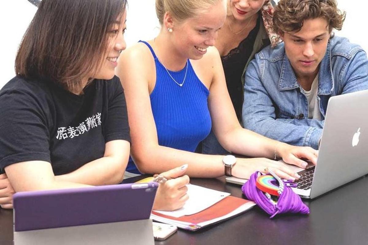 um grupo de pessoas sentadas ao redor de uma mesa com um laptop