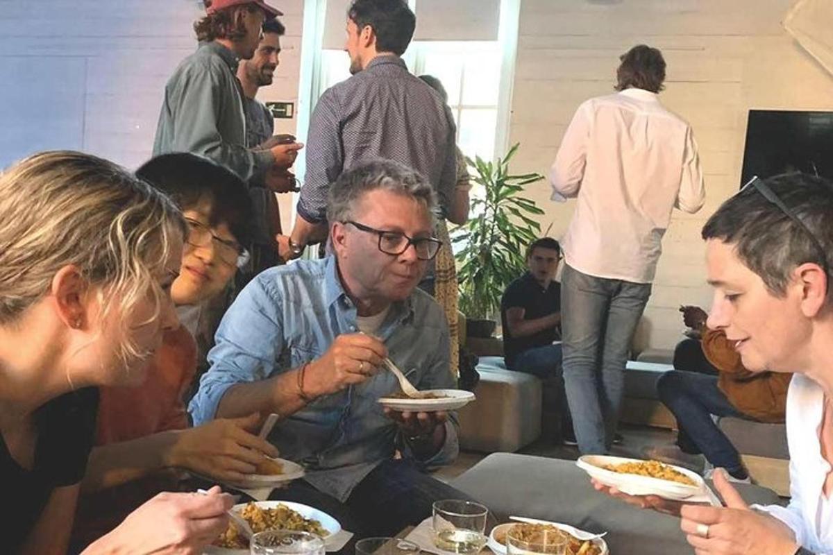 isang grupo ng mga tao na nakaupo sa paligid ng isang mesa na kumakain ng pagkain