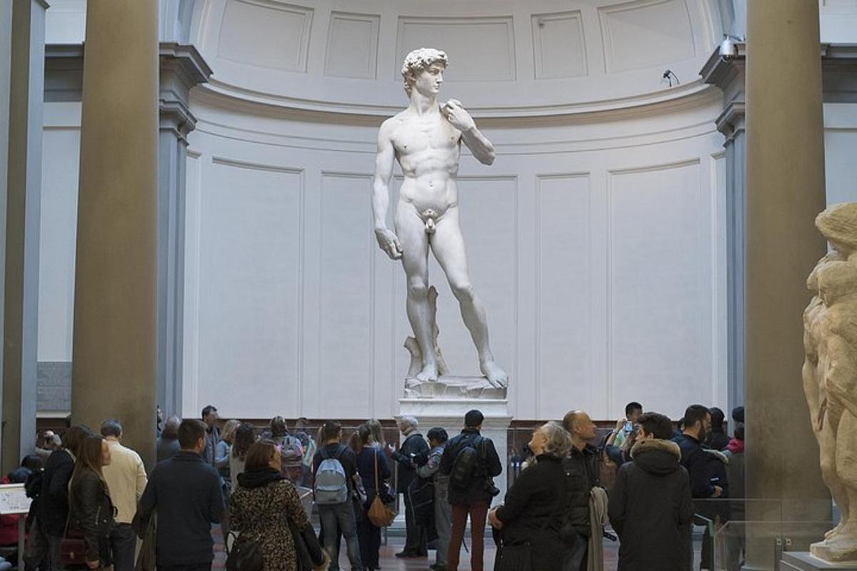 a crowd of people looking at a statue in a museum