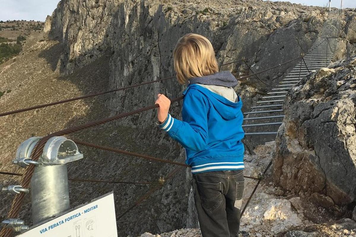 Ένα μικρό παιδί στέκεται σε ένα σχοινί κοντά σε μερικά σκαλοπάτια