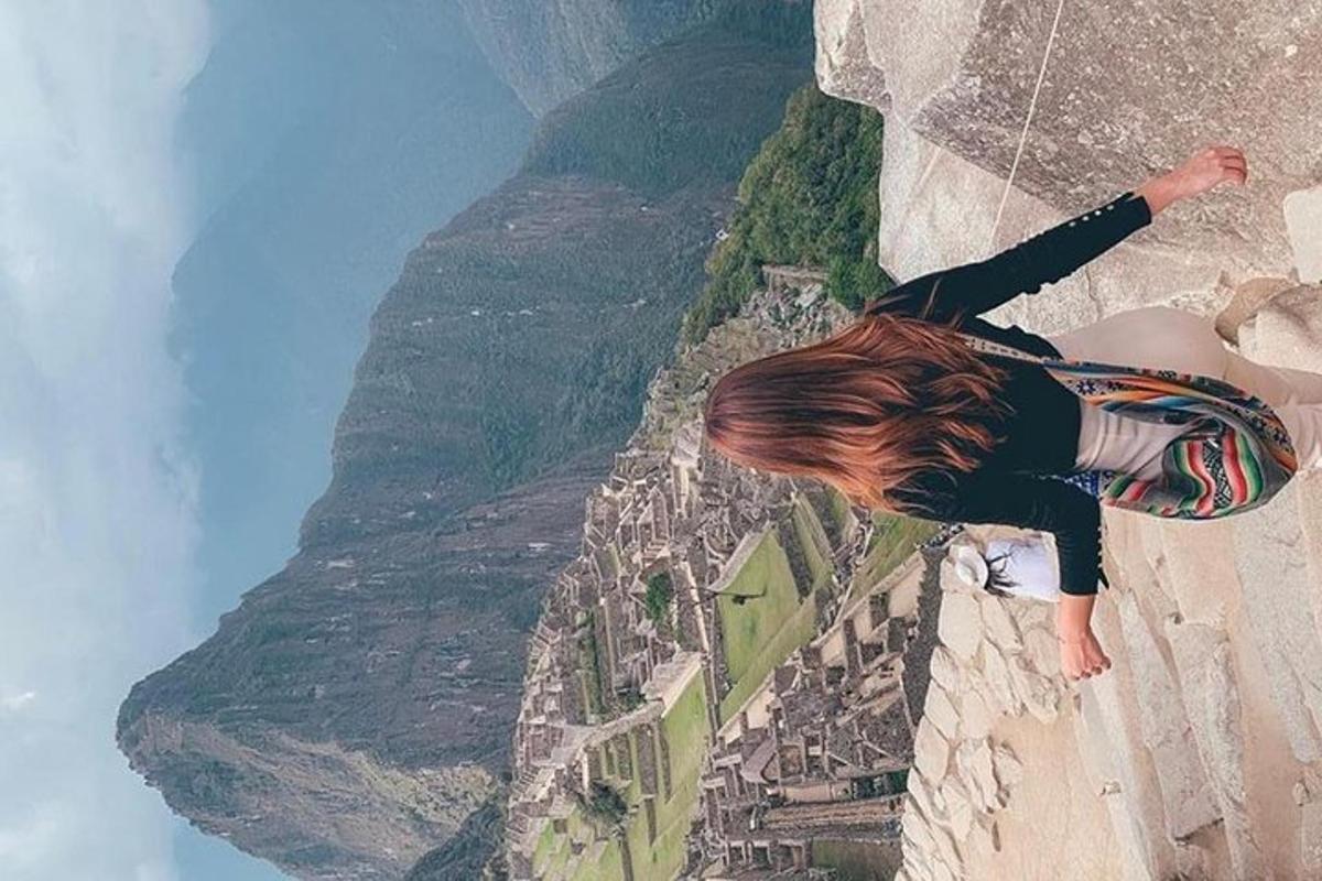Una mujer parada en un acantilado mirando las montañas