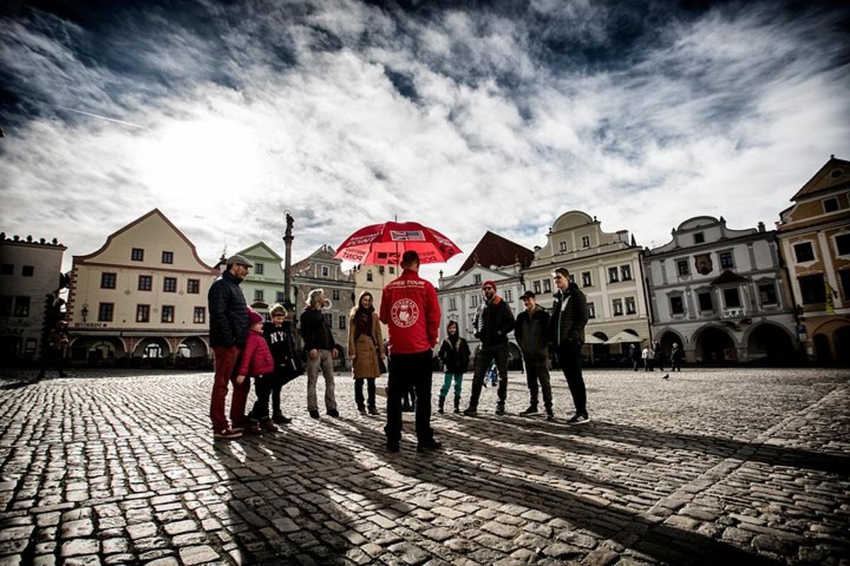 skupina lidí stojících na ulici s červeným deštníkem