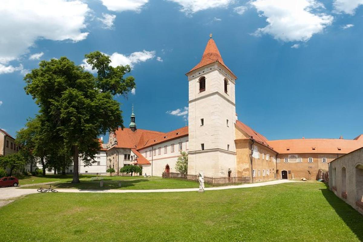 un grande edificio con una torre e un campo erboso