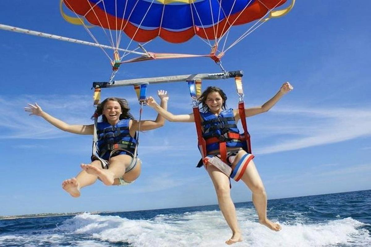 duas meninas estão pulando na água com um paraquedas