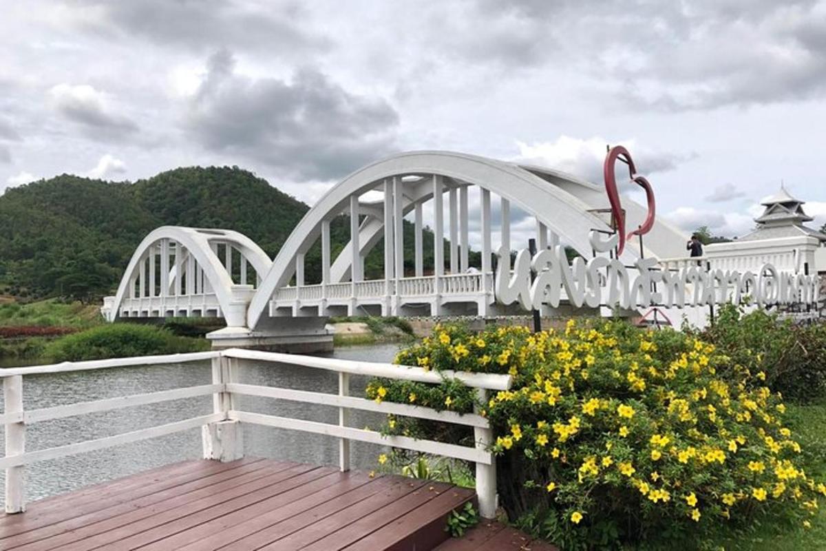 một cây cầu trắng bắc qua một dòng sông có hoa