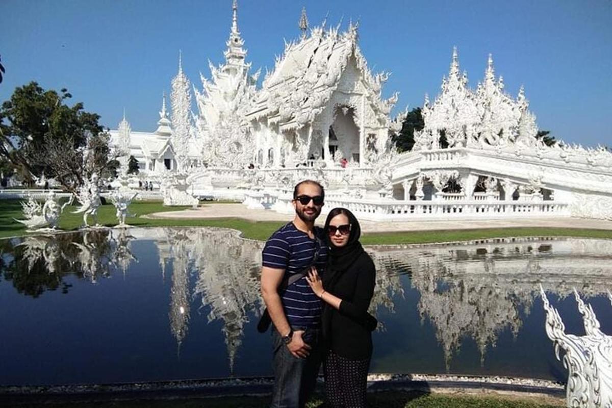 un uomo e una donna in posa davanti a un tempio bianco