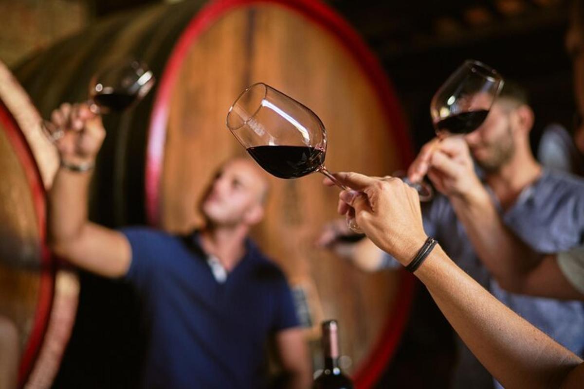 Tres personas sosteniendo copas de vino en una bodega.