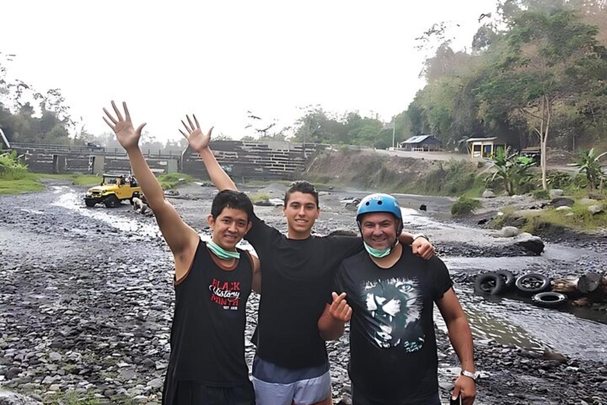 a group of three men standing next to a river