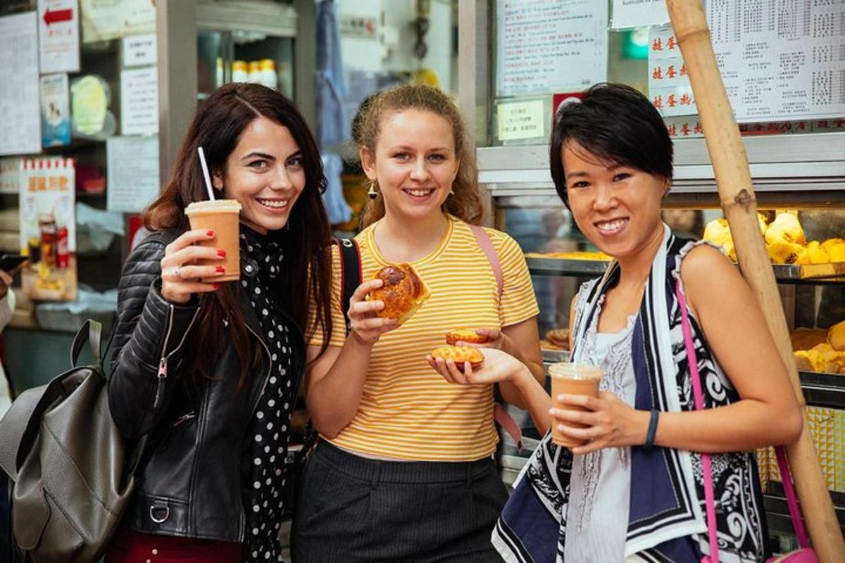 tiga wanita berdiri di kedai sambil memegang donat dan minuman