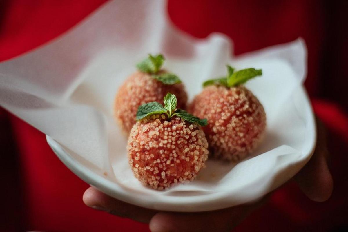 seseorang yang memegang dua buah strawberi dalam pinggan putih