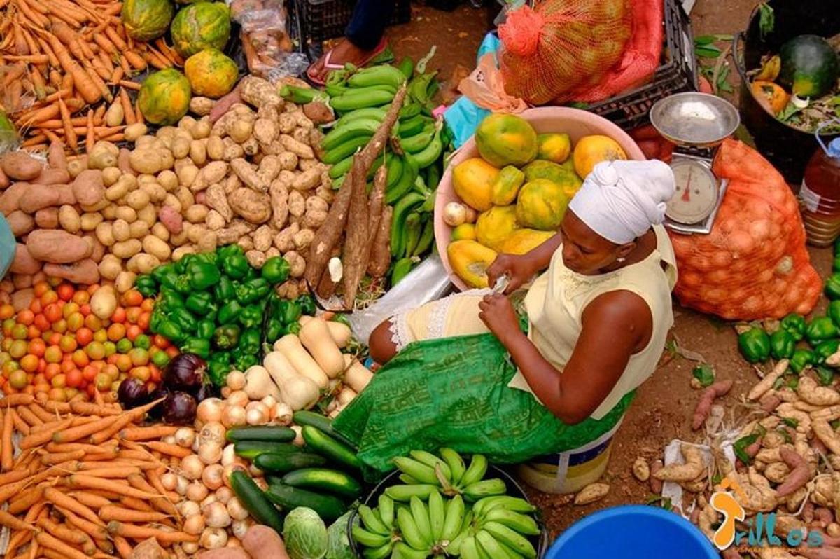 a woman sitting in front of a pile of fruits and vegetables