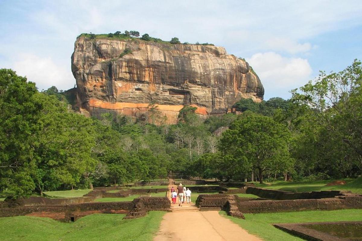 a group of people walking in front of a large rock