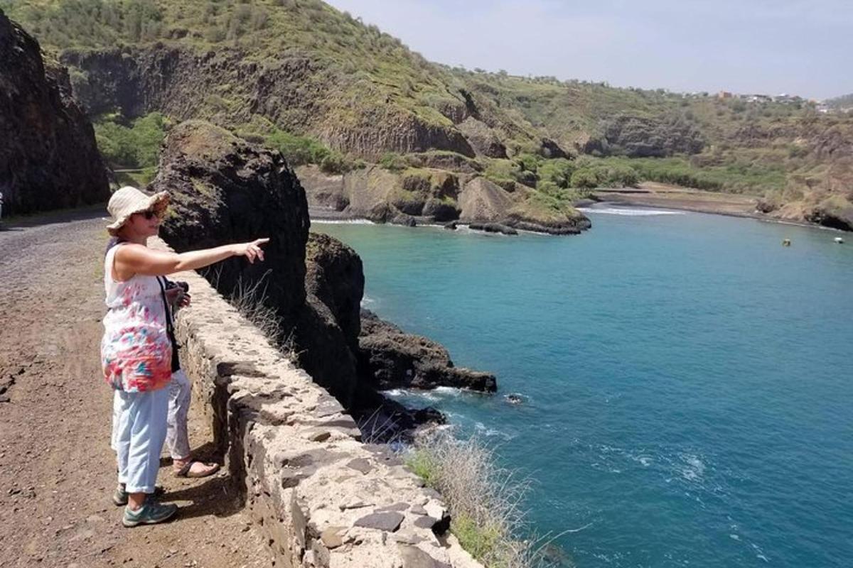 a woman standing on a wall pointing at the ocean