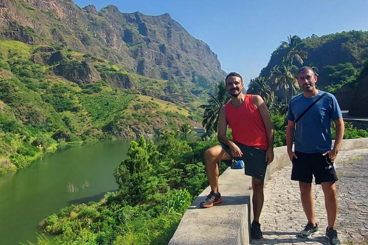 two men standing on a ledge next to a river