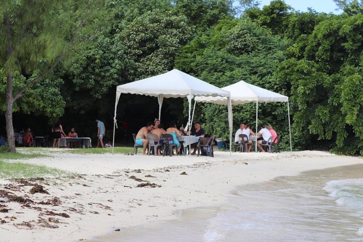 un gruppo di persone sedute sotto tende bianche su una spiaggia