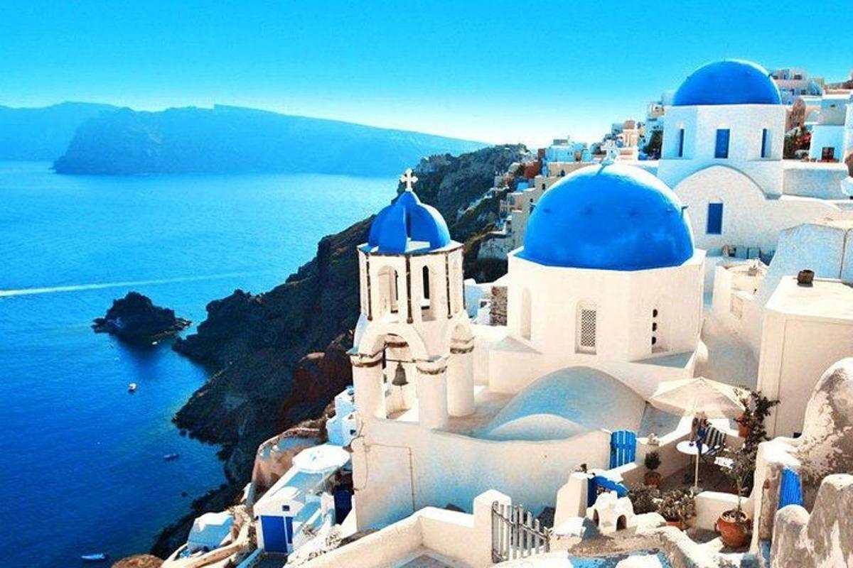un gruppo di edifici bianchi con cupole blu e l'oceano