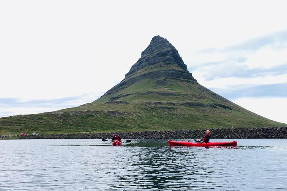 two people in red boats in the water with a mountain