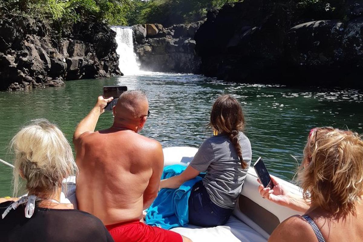 sekumpulan orang di atas bot di hadapan air terjun