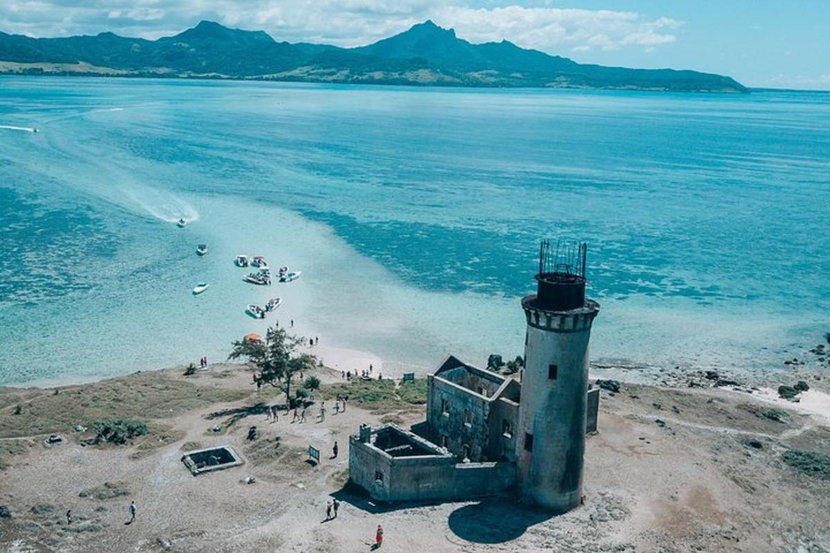 Un faro en una playa con gente en el agua.