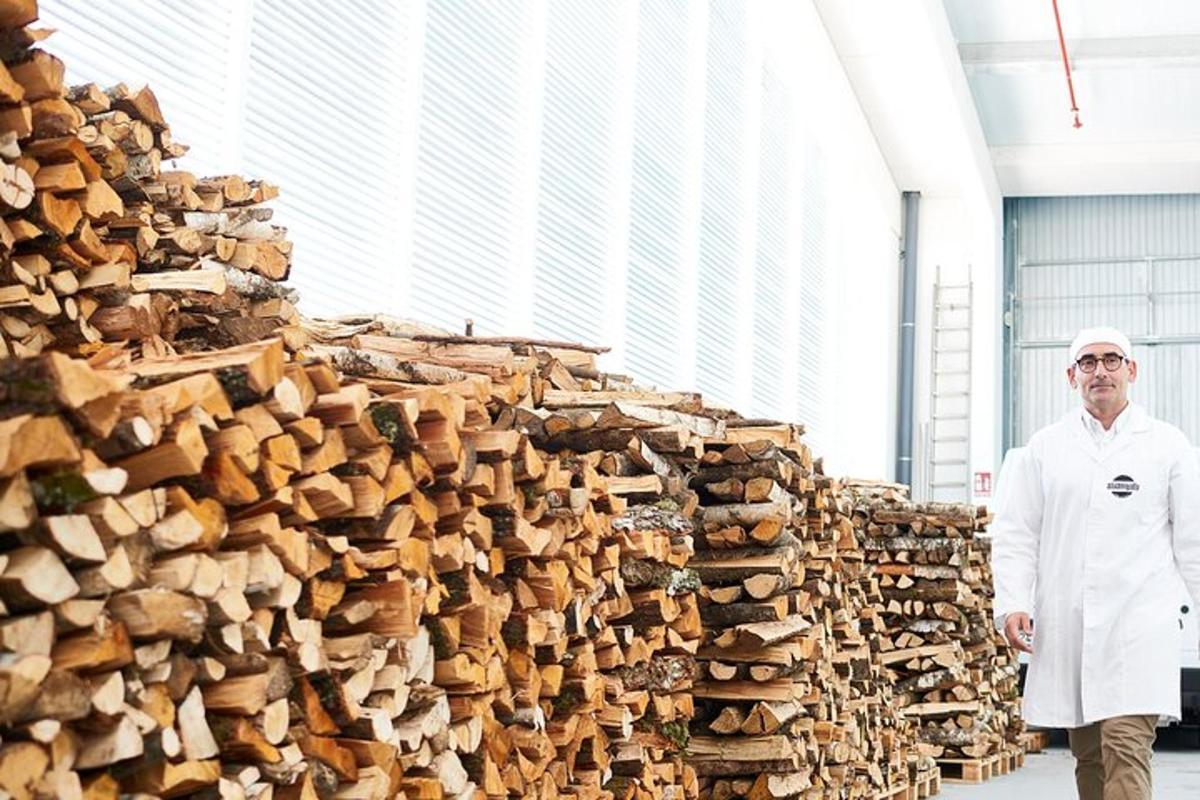 a man in a white coat standing in front of a pile of wood