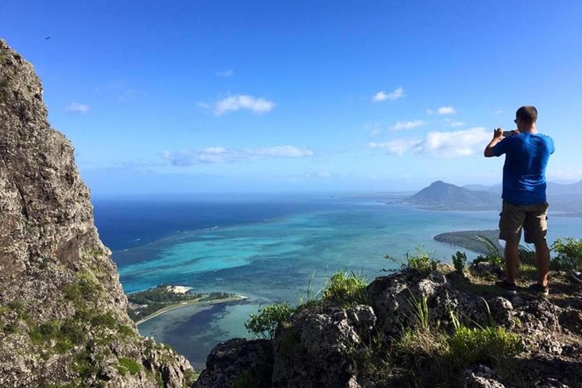 a man taking a picture of the ocean from a mountain