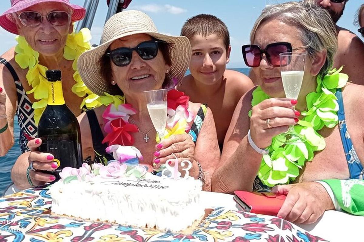 un gruppo di persone sedute a un tavolo con una torta di compleanno