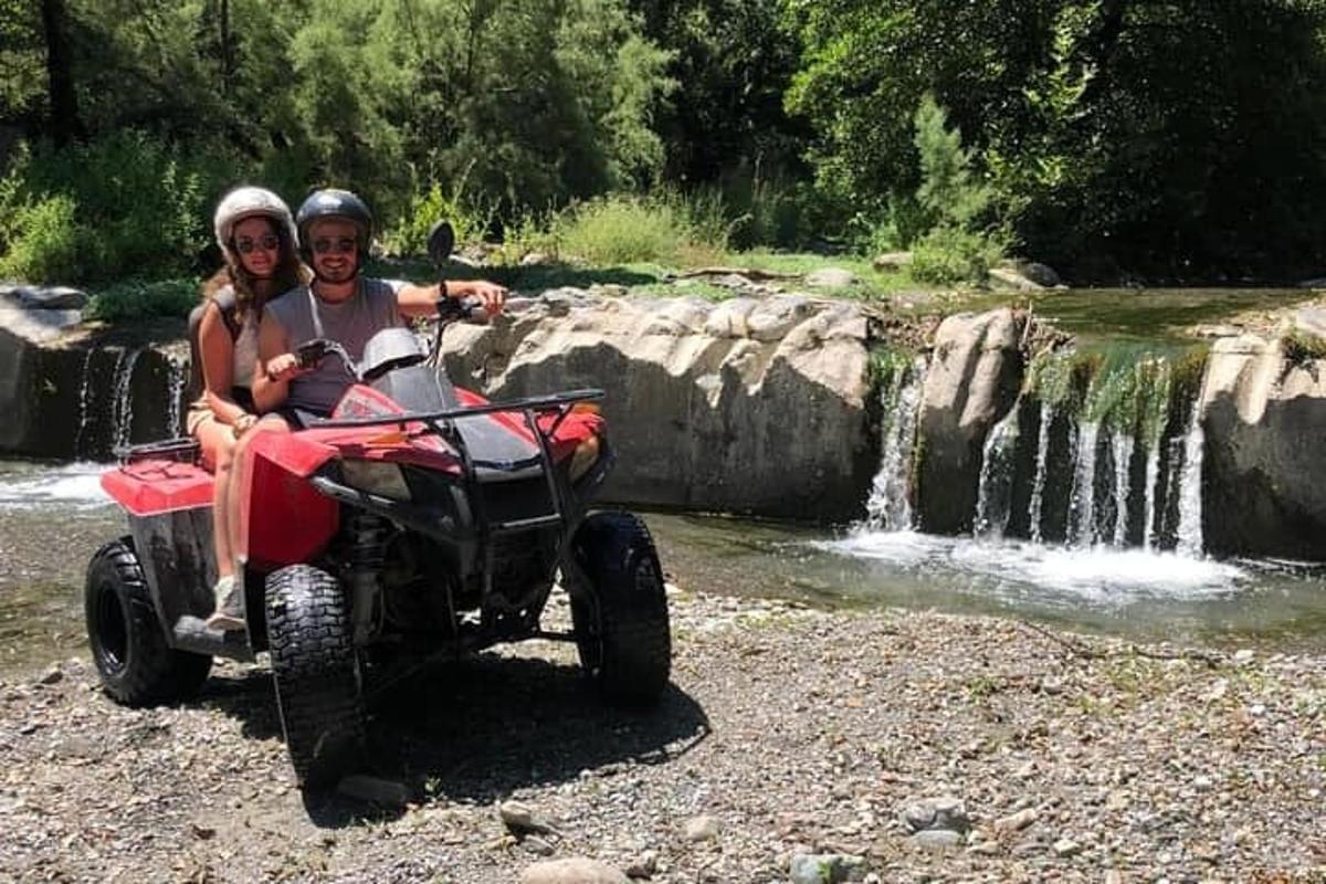 moški in ženska na štirikolesniku pred slapom