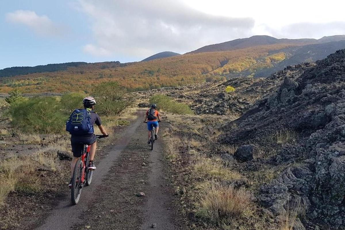 dvaja ľudia jazdiaci na bicykloch po prašnej ceste