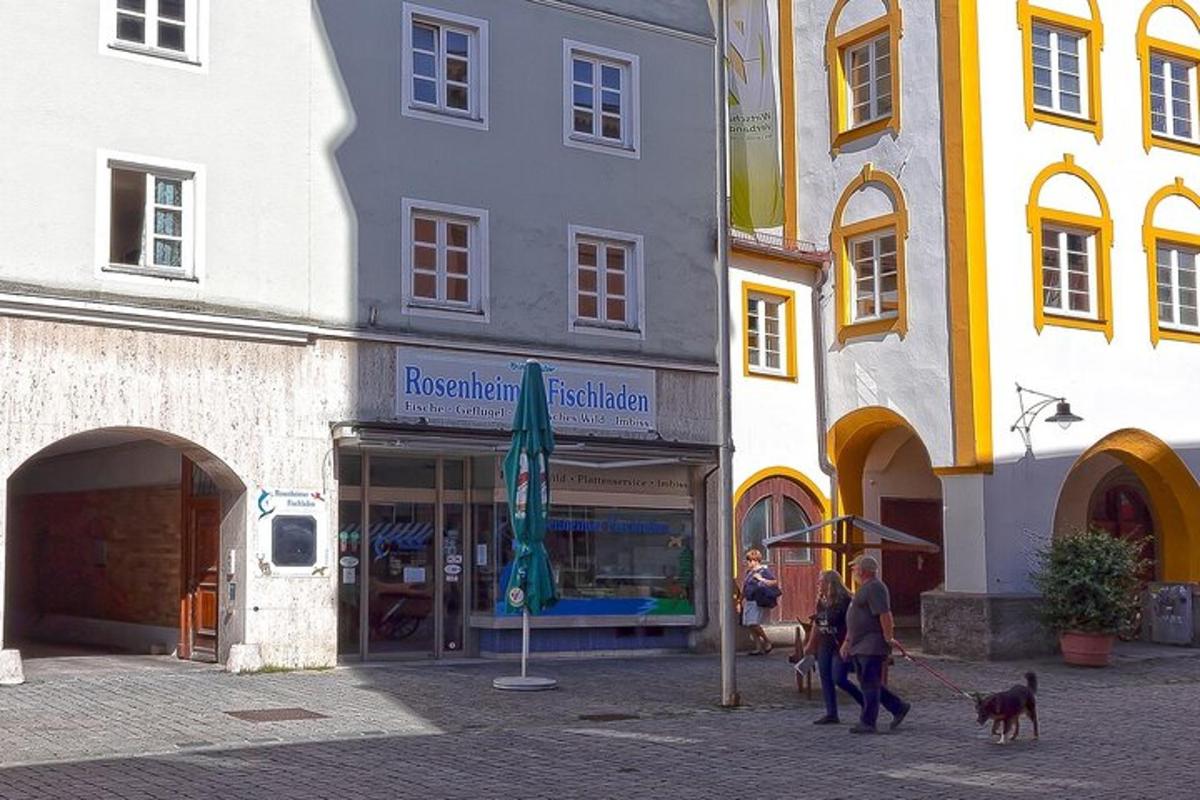 paar inimest jalutavad koeraga hoone ees