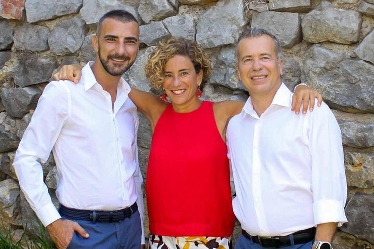 due uomini e una donna in piedi accanto a un muro di pietra