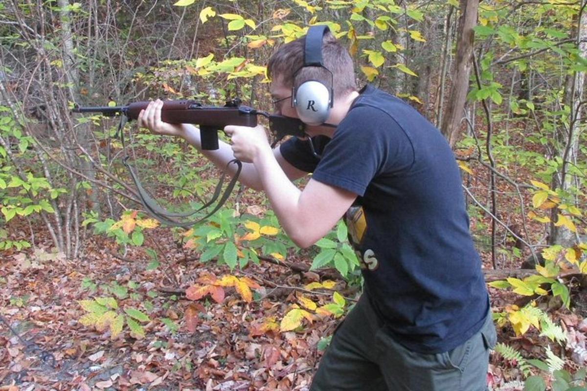 ein Mann mit Kopfhörern und einer Waffe im Wald
