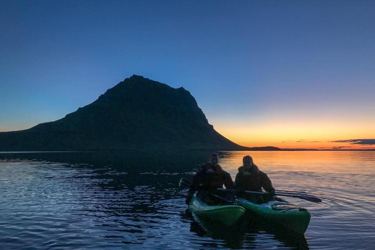 two people in a kayak on the water at sunset