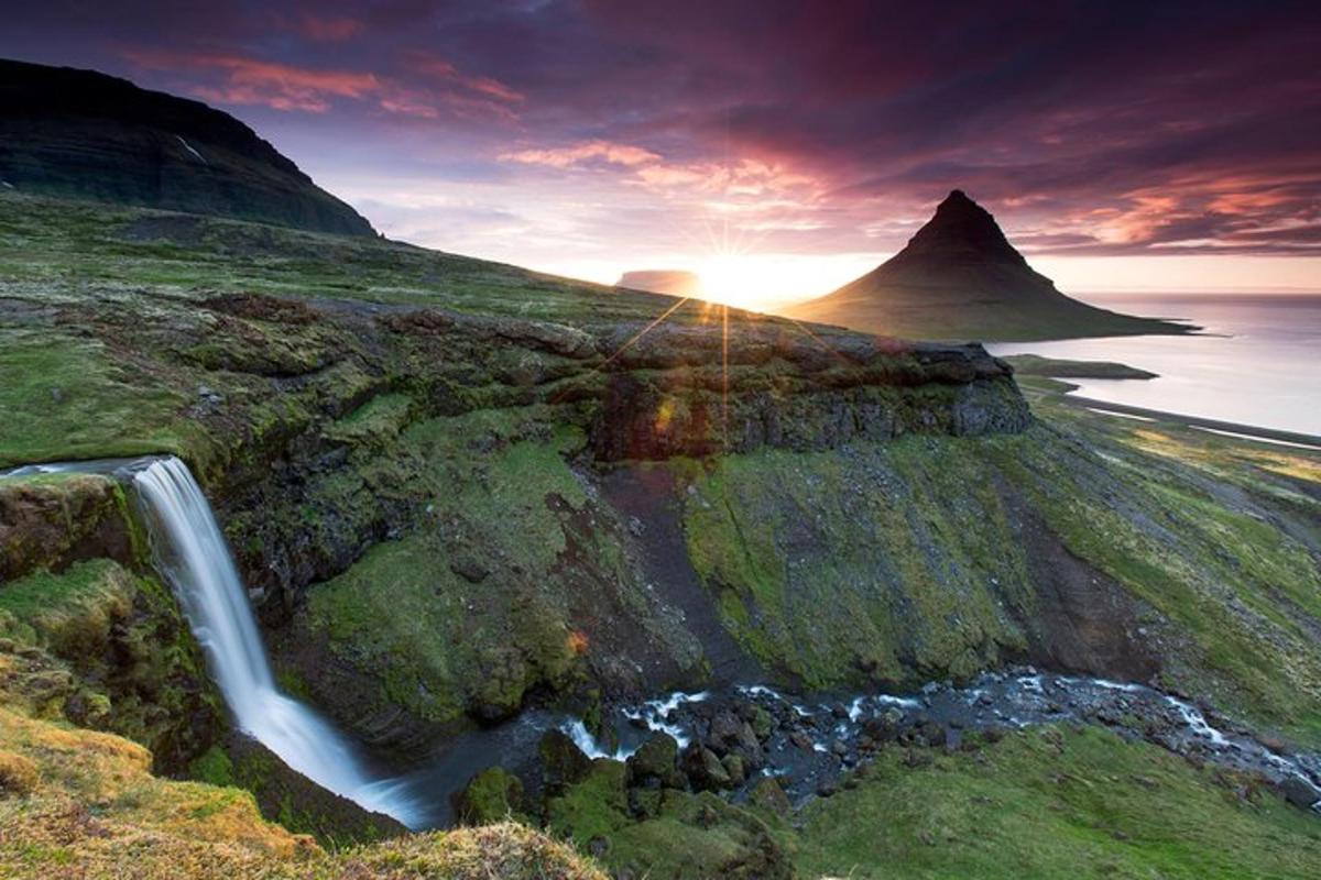 a waterfall on a hill with a mountain in the background