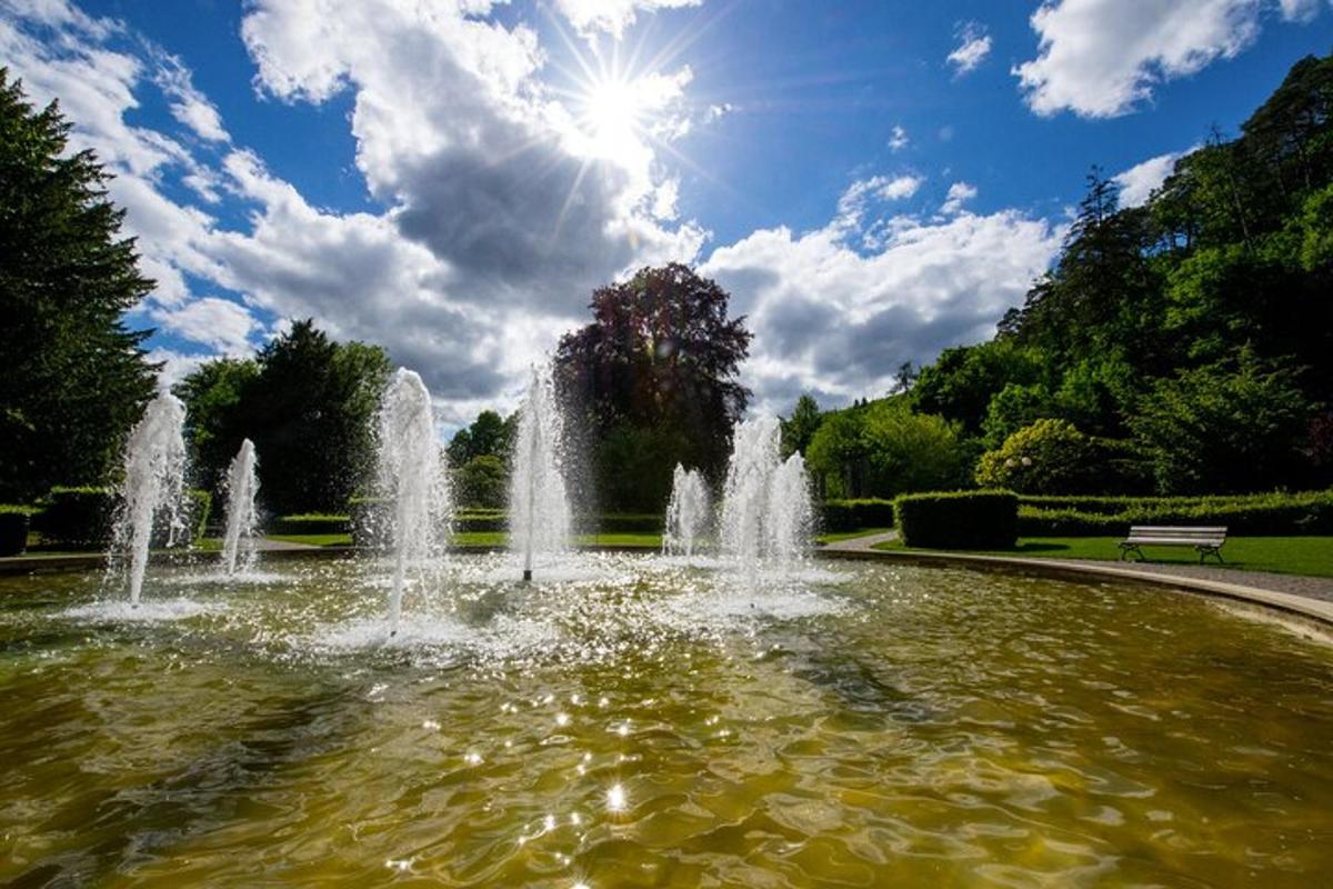 a fountain in a park with the sun behind it