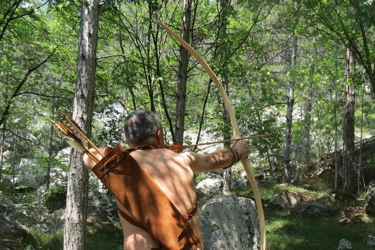 muž s lukem a šípem v lese