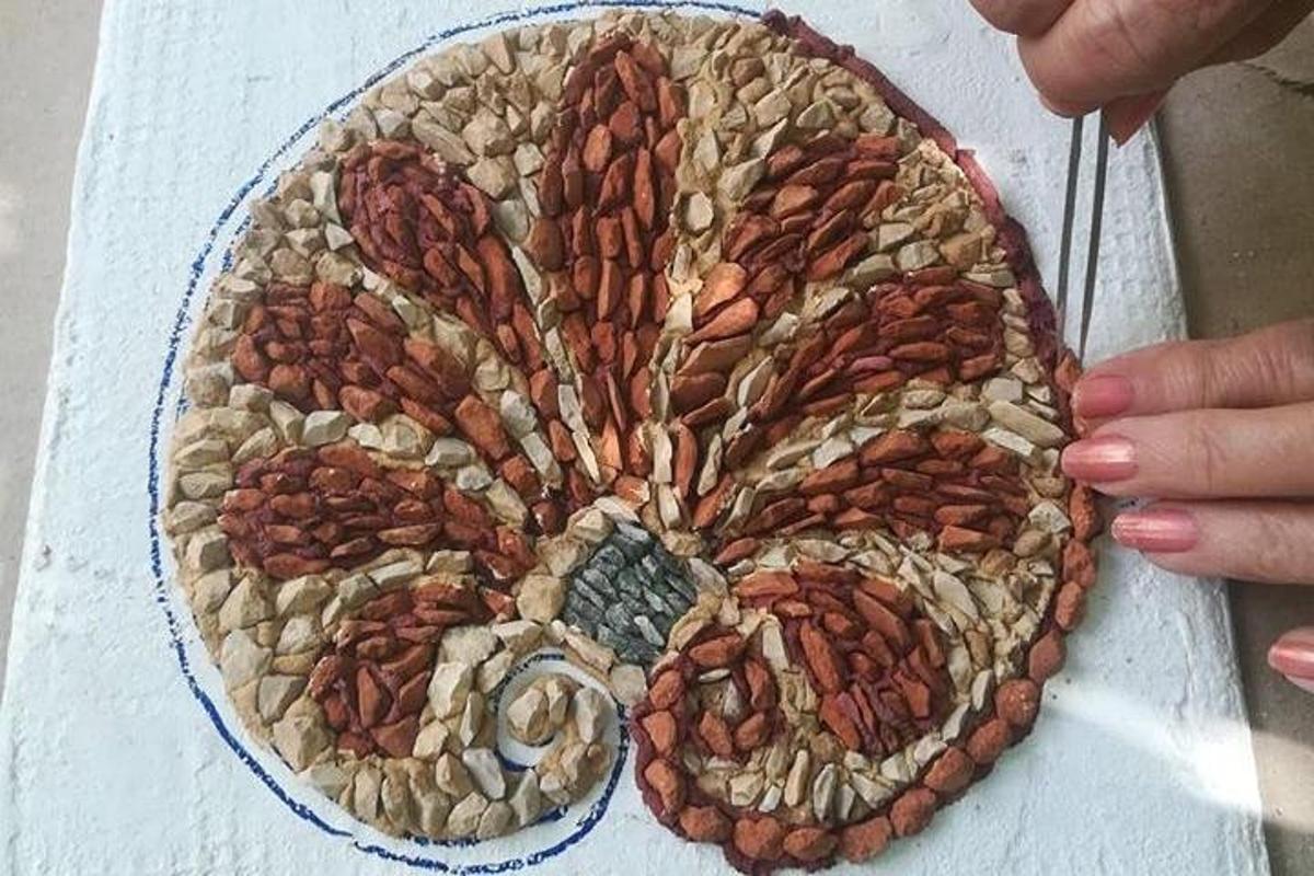 Una persona sosteniendo un plato de mosaico con nueces encima.