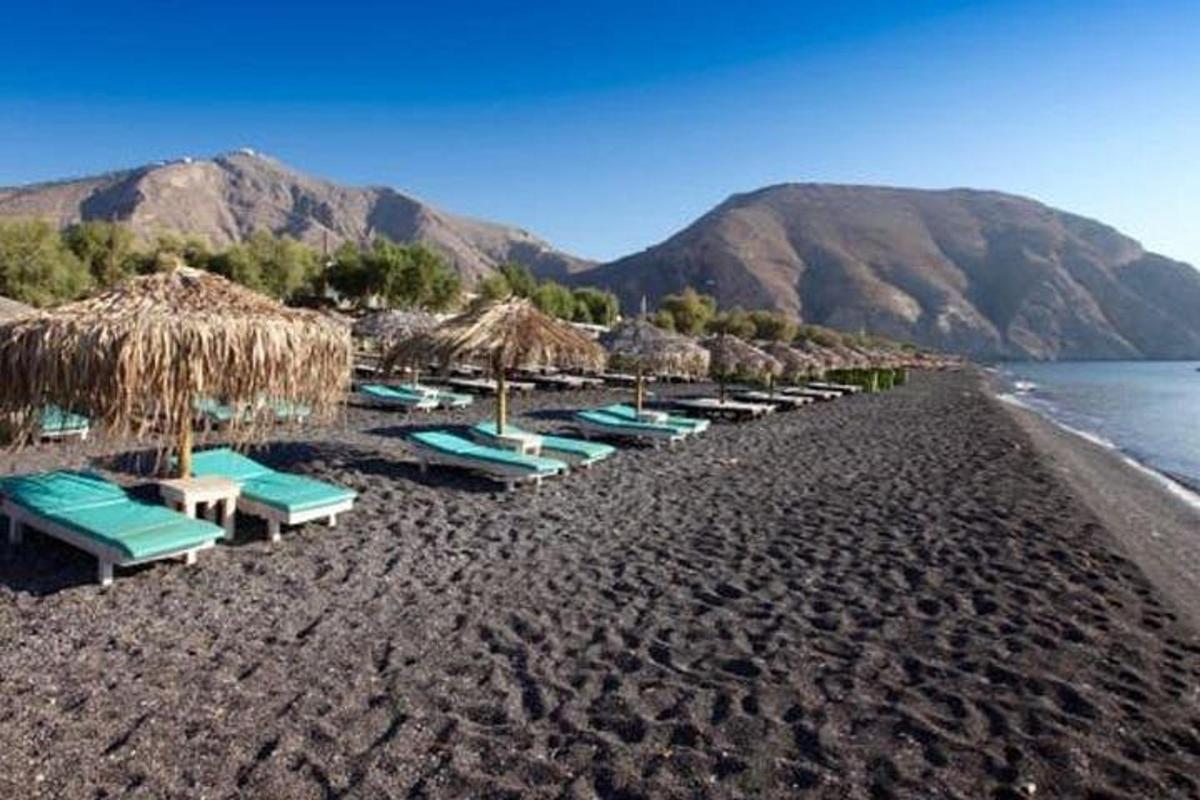 a beach with chairs and straw umbrellas and the water