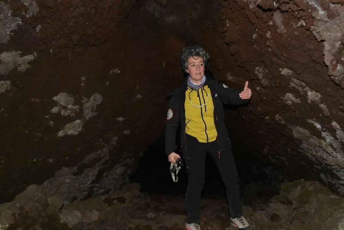 muž stojící v jeskyni a ukazující palec nahoru