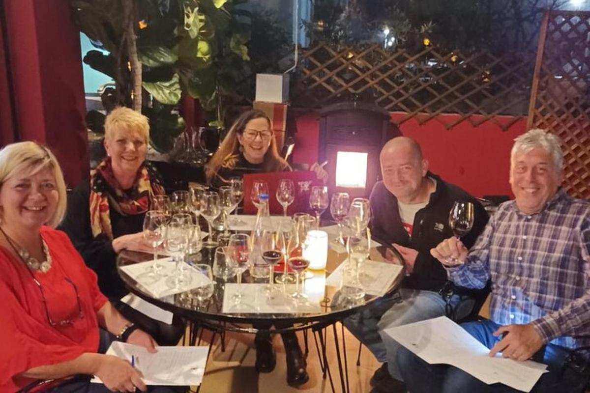 un gruppo di persone sedute attorno a un tavolo con bicchieri di vino