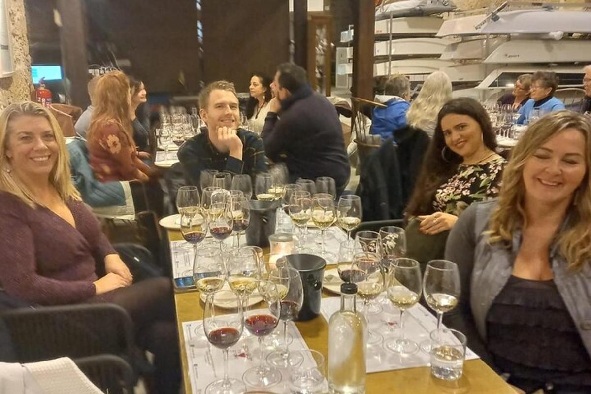 un gruppo di persone sedute a un tavolo con bicchieri di vino