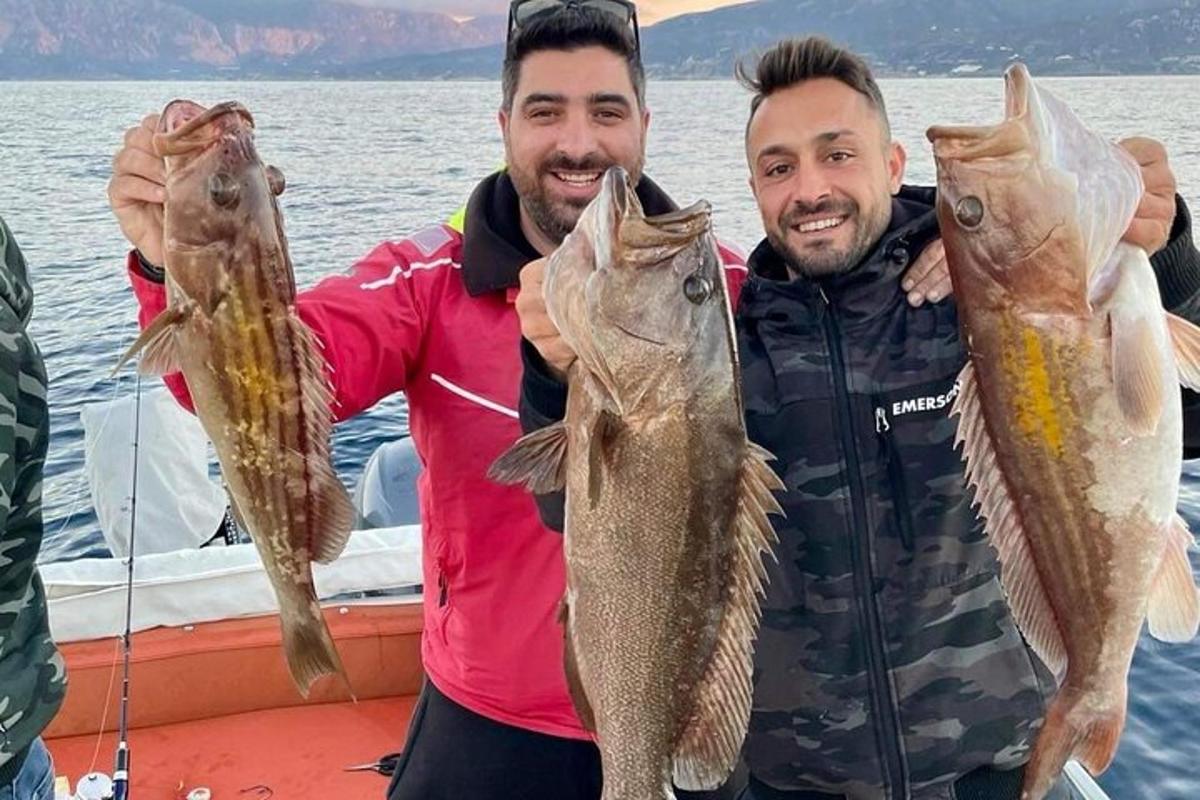 ボートの上で2匹の魚を持ち上げている2人の男性