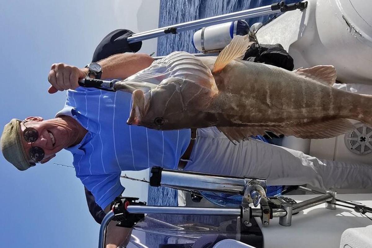 un uomo che tiene un pesce in cima a una barca