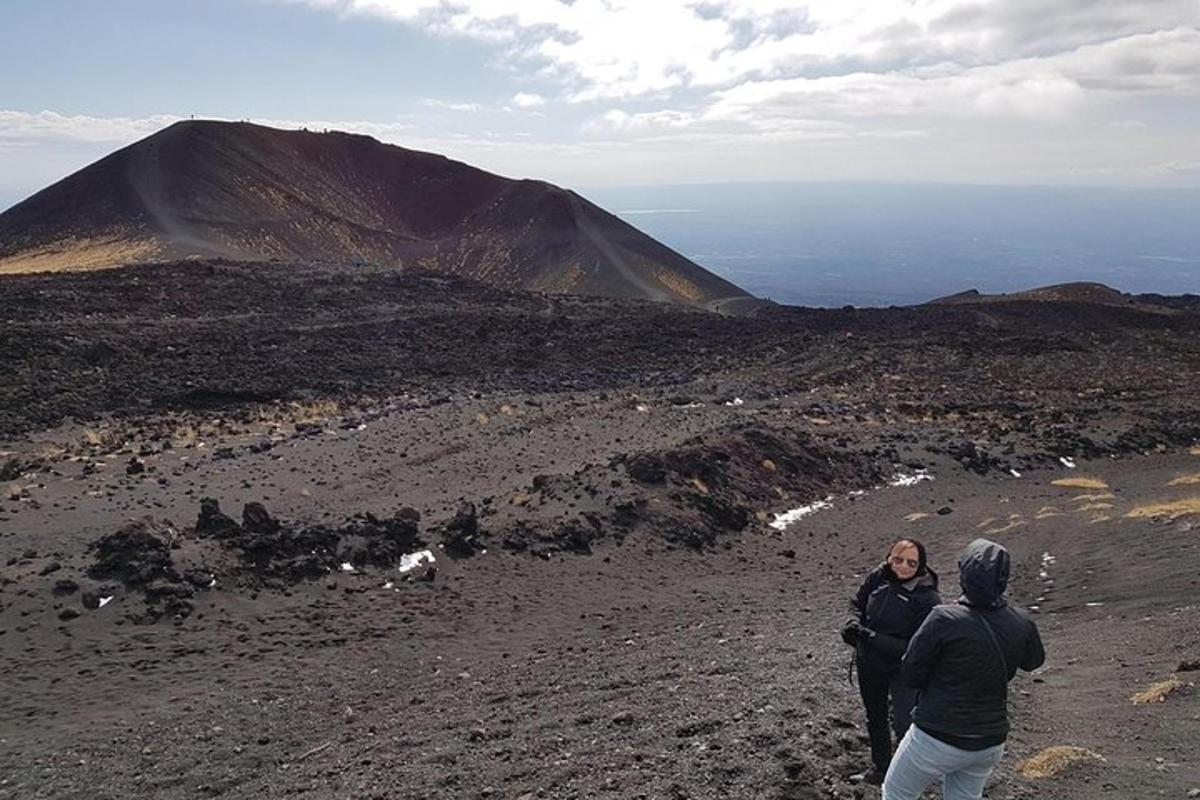 twee mensen lopen op een berg met de oceaan op de achtergrond