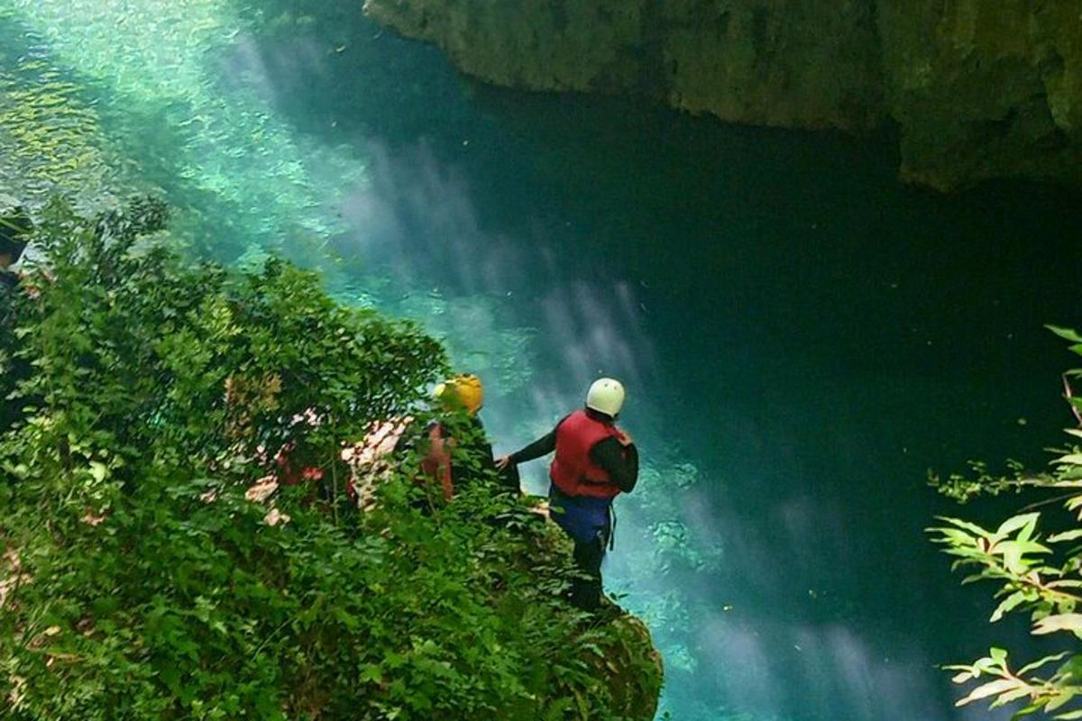 un uomo in piedi su una scogliera vicino a una cascata