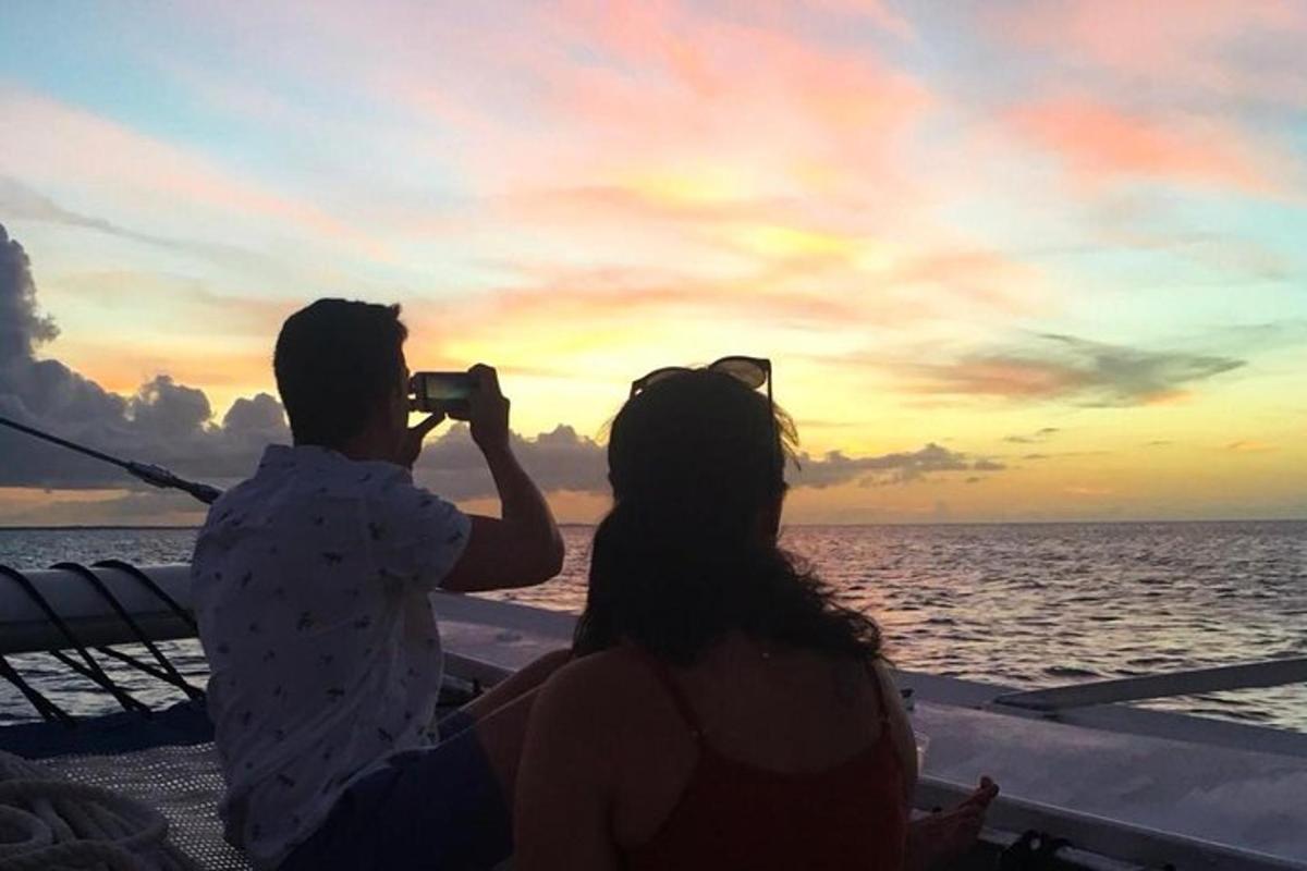 a man and woman taking a picture of the sunset on a boat