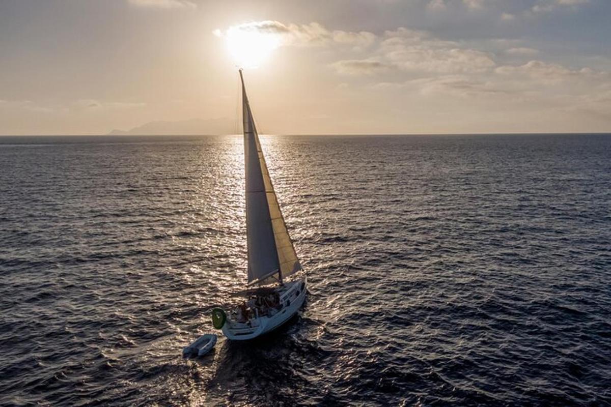 un velero en el océano con el sol en el cielo