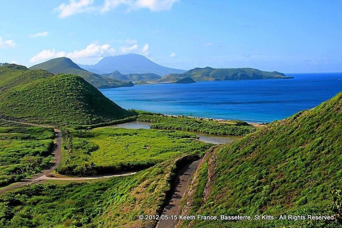 a view of the ocean from a hill with a road