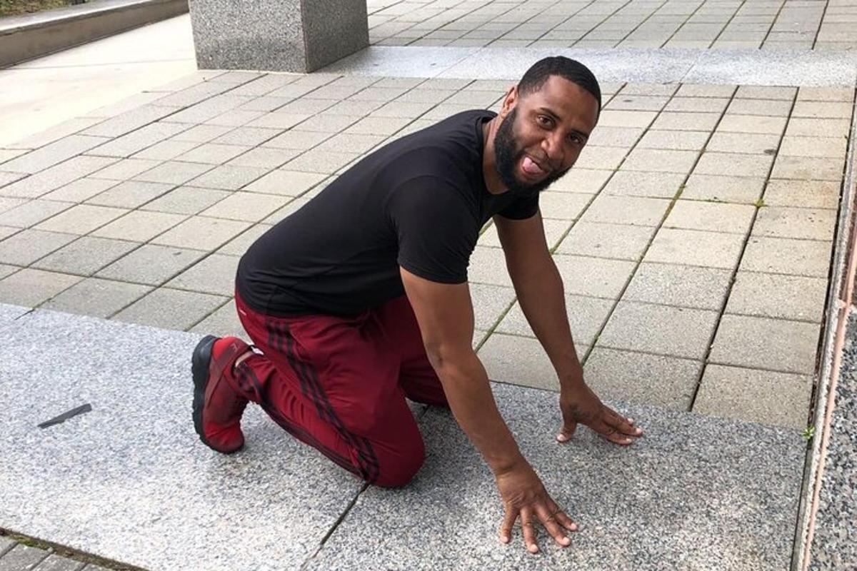 a man kneeling on the ground on a sidewalk