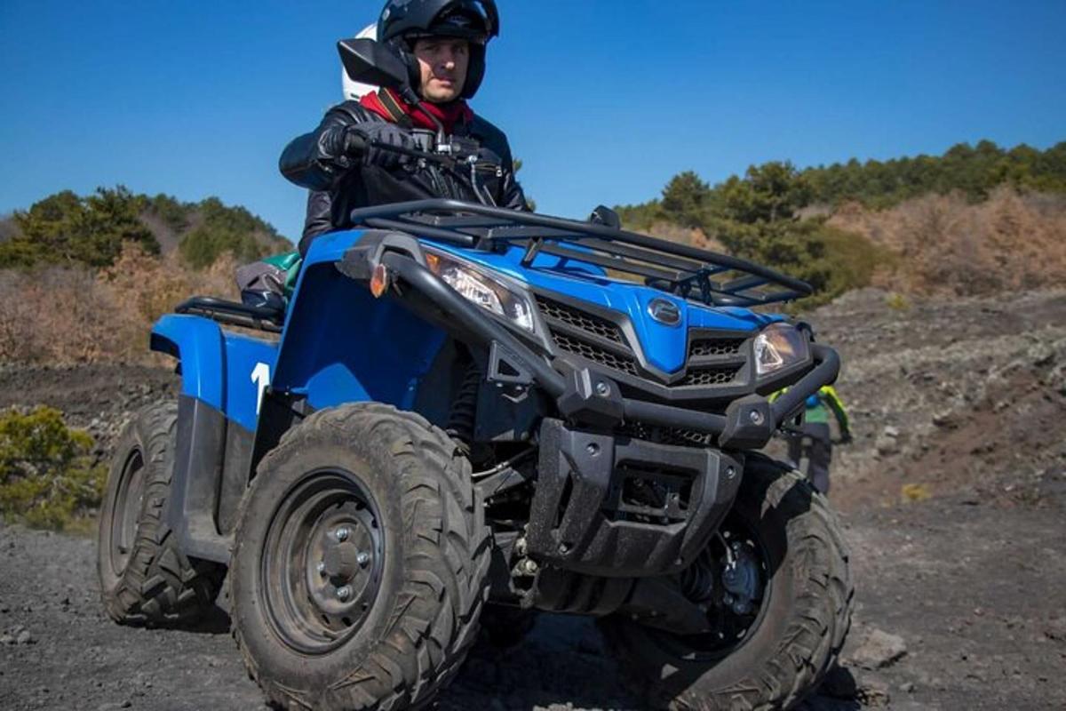 човек, седнал на ATV на черен път